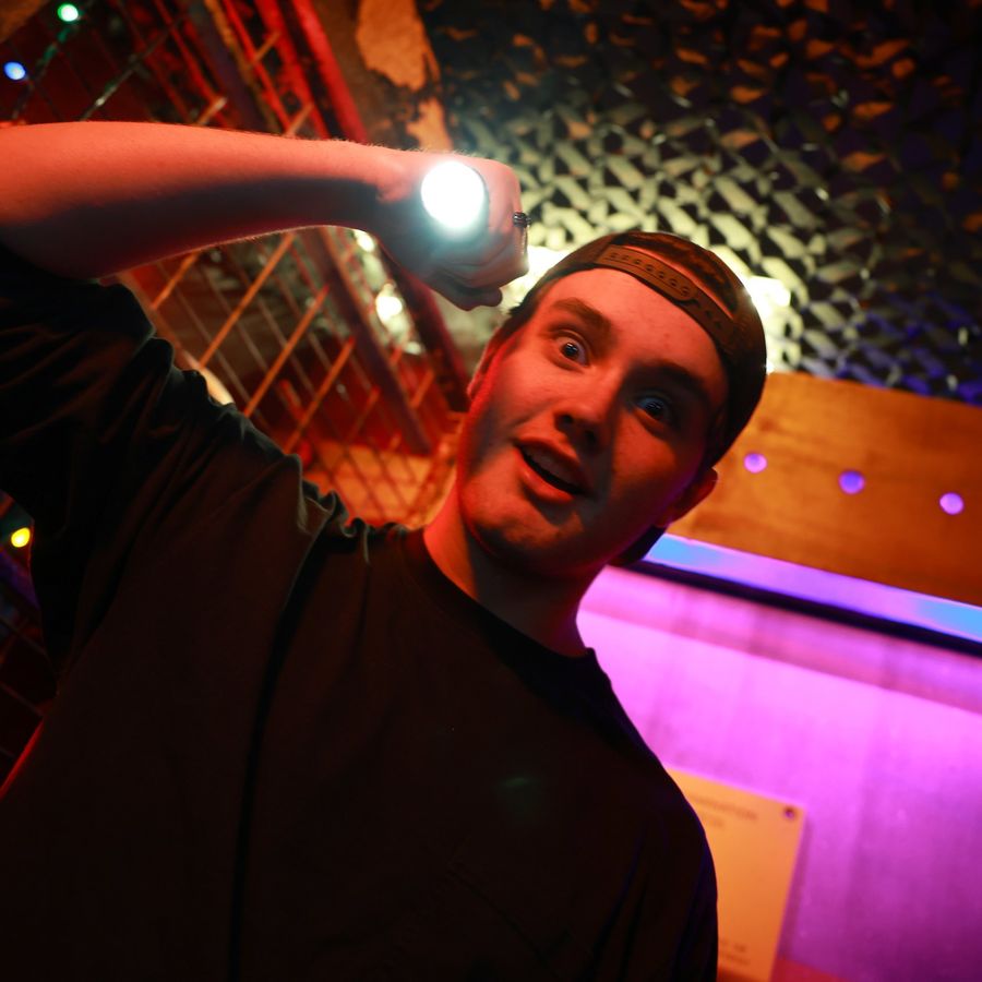 A man with a flashlight investigating the Alien Escape room