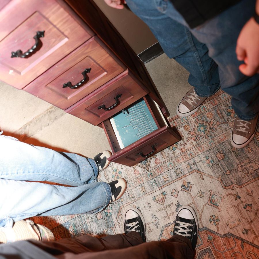 A team finding a hidden drawer clue in the Blood Money escape room